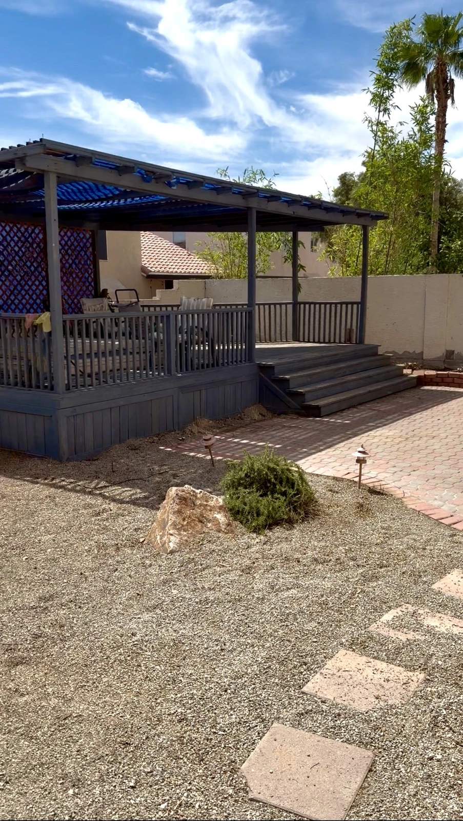 Same backyard patio area after renovation, finished with desert gravel and a stepping-stone path