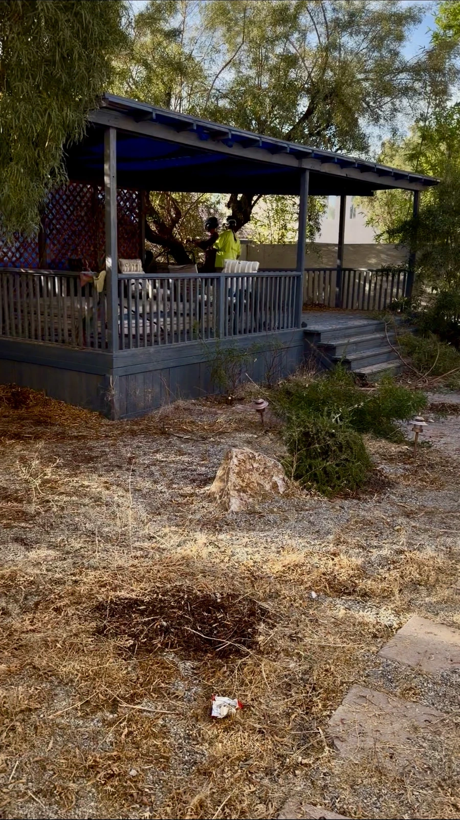 Backyard covered patio area before renovation, with bare dirt and cleared brush