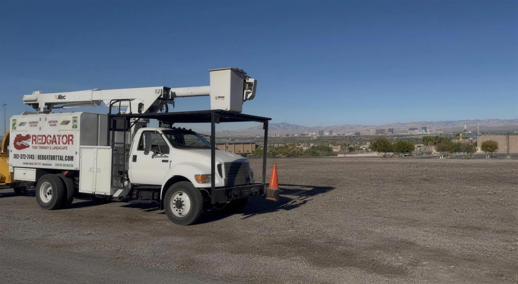 RedGator bucket truck parked on an open lot with the Las Vegas valley and Strip skyline in the background