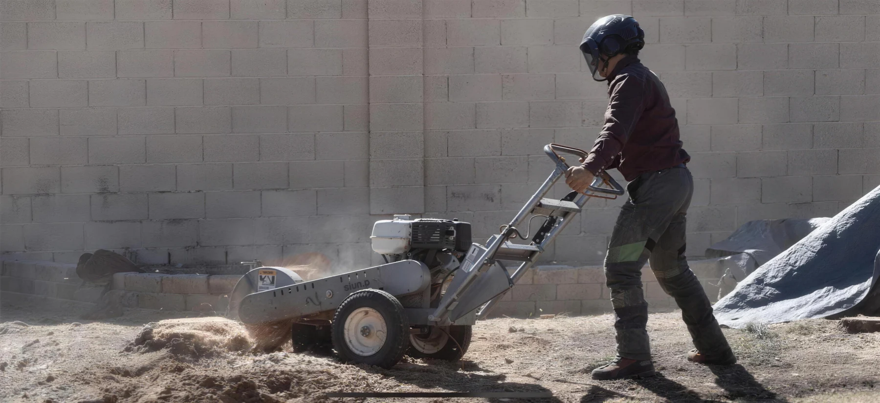 Crew member operating a stump grinder